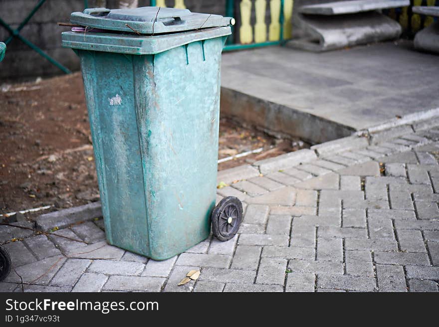 Green trash cans are on the side of the road. It looks worn out with the color starting to fade. Green trash cans are on the side of the road. It looks worn out with the color starting to fade.