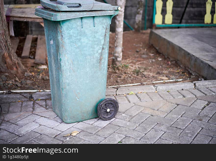 Green trash cans are on the side of the road. It looks worn out with the color starting to fade. Green trash cans are on the side of the road. It looks worn out with the color starting to fade.