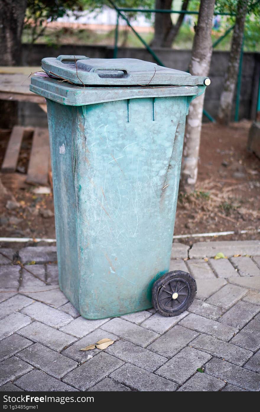 Green trash cans are on the side of the road. It looks worn out with the color starting to fade. Green trash cans are on the side of the road. It looks worn out with the color starting to fade.