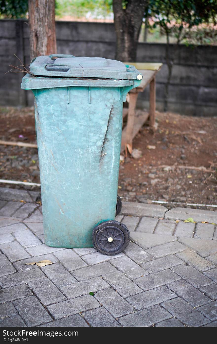 Green trash cans are on the side of the road. It looks worn out with the color starting to fade. Green trash cans are on the side of the road. It looks worn out with the color starting to fade.