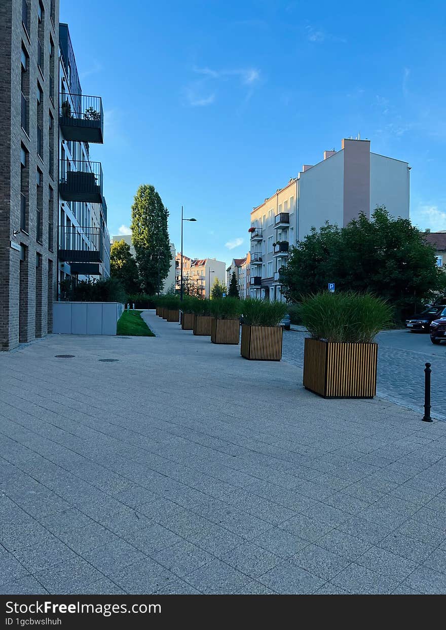 Gdansk, Poland - 08.08.2022: A modern residential area in the city center, a pedestrian zone made of tiles, cubic flowerpots with