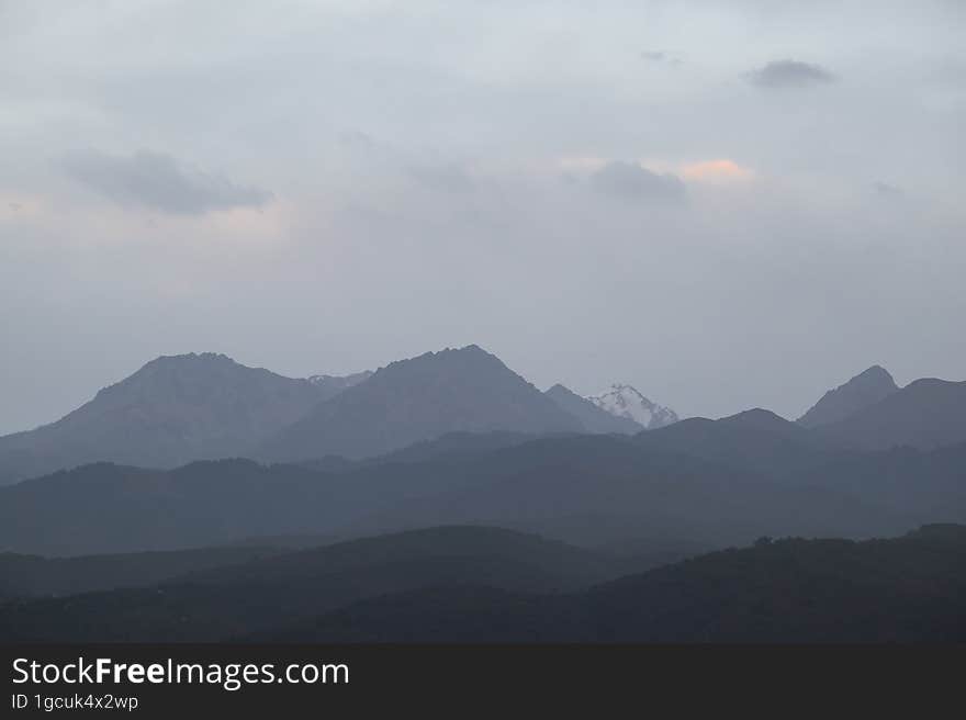 Landscape of the Trans-Ili Alatau mountains on an early cloudy morning in the morning fog