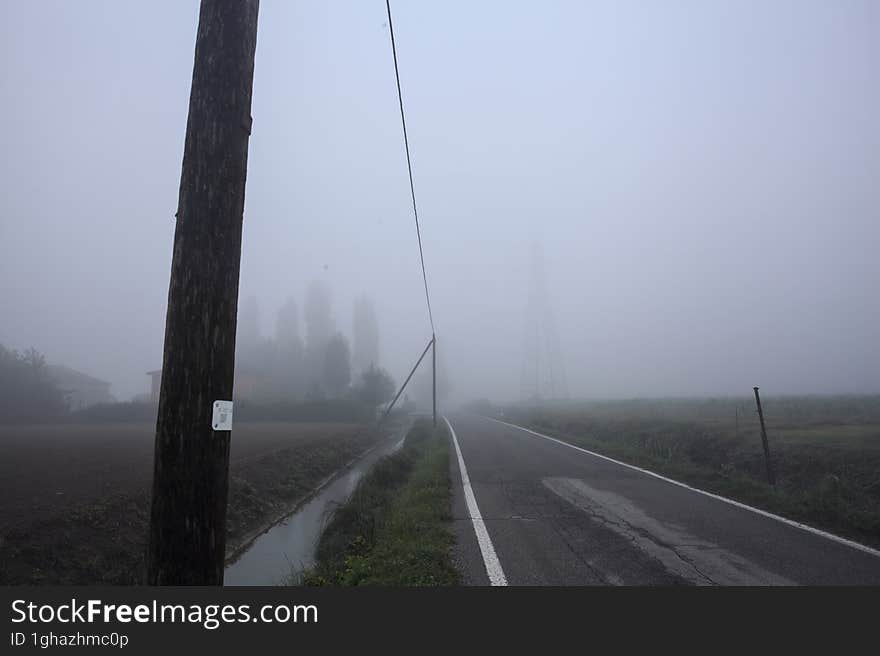 Group of houses by the edge of a country road on a foggy day in autumn