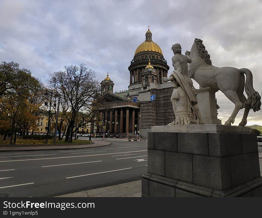 Statue Of A Man With A Horse Against The Backdrop Of The Cathedral In St. Petersburg