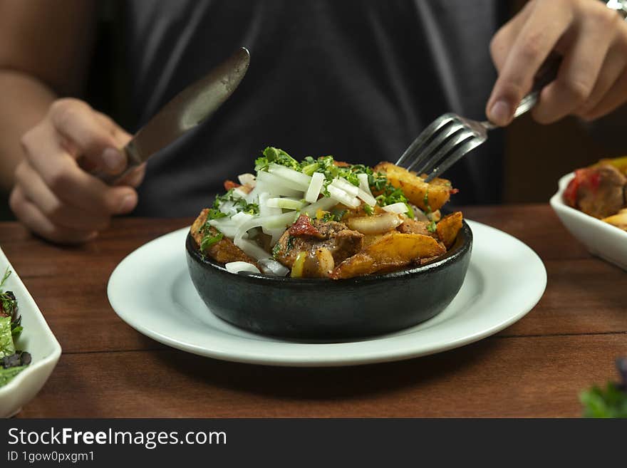 Man eating Beef stew with potatoes, carrots and herbs on black background with copy