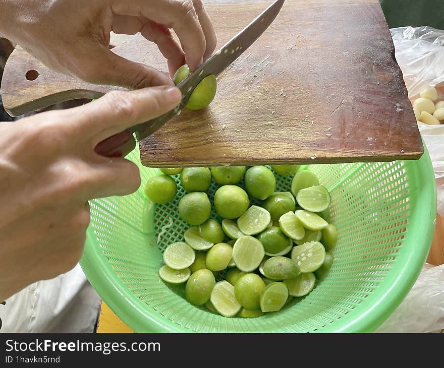 A man& x27 s hand cuts a lime using a sharp knife