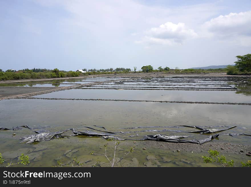 View Of Salt Fields Submerged In Water During A Clear Sky During The Day