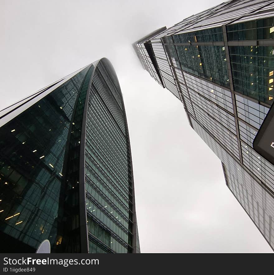 two skyscrapers with the top in the fog