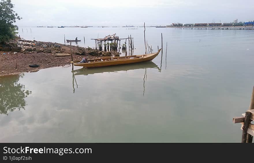 A serene image of a fishing boat gently floating on calm, glistening waters at sunrise.