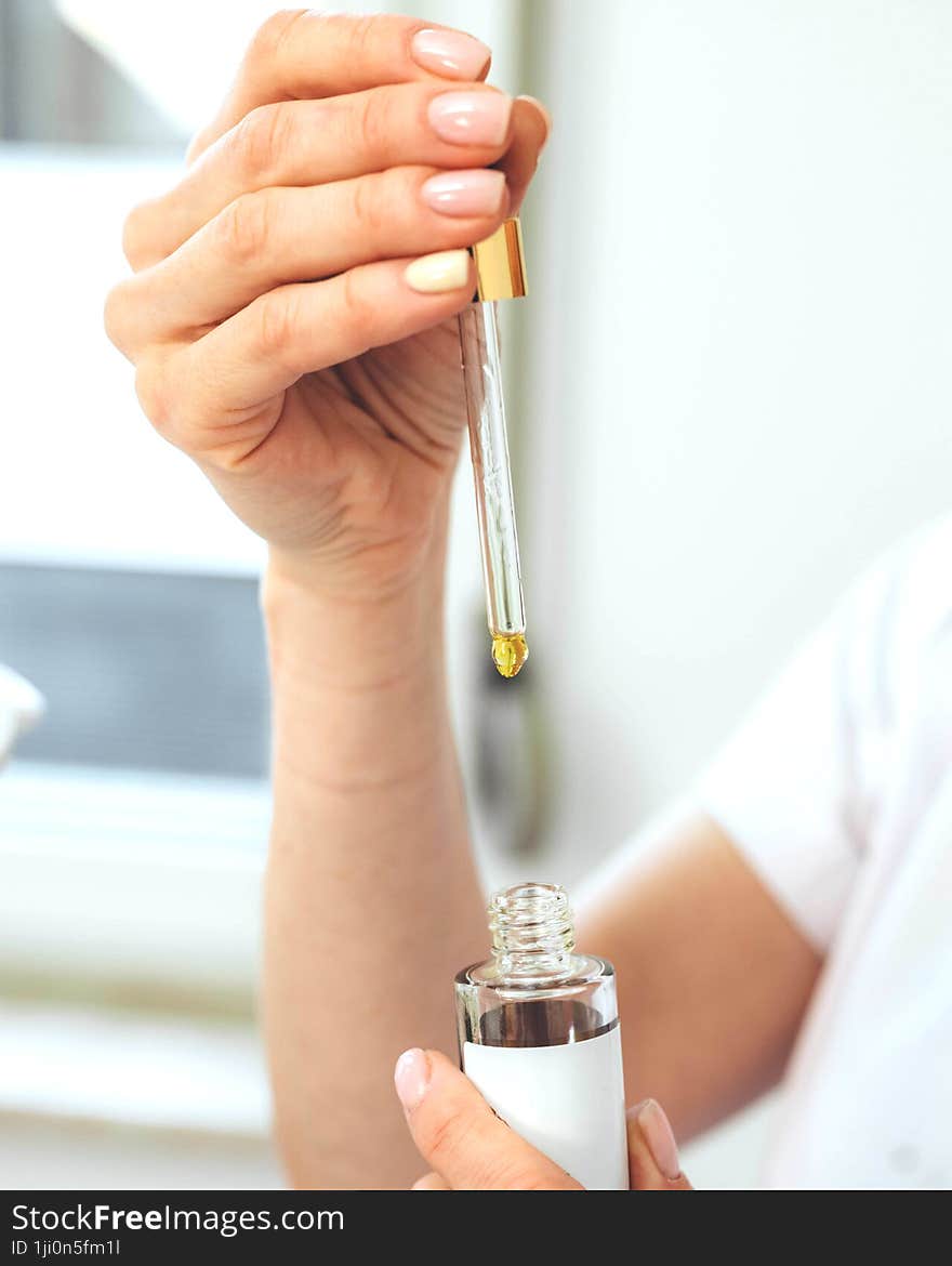 A woman hand delicately holds a bottle with a dropper