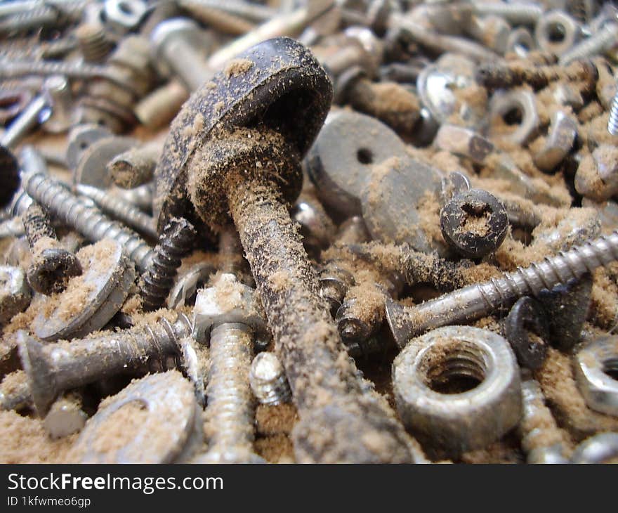 A pile of old bolts and nuts at the bottom of a box in the garage.