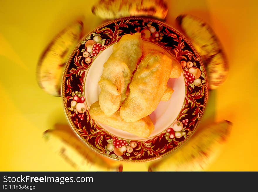 Serving of fried bananas on a small plate with 5 unpeeled bananas around it.