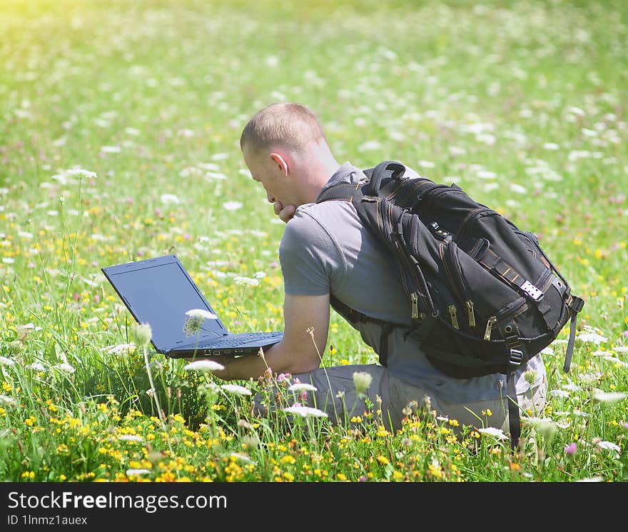 Young man working with laptop on nature background