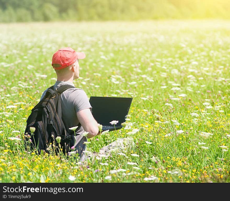 Young man working with laptop on nature background