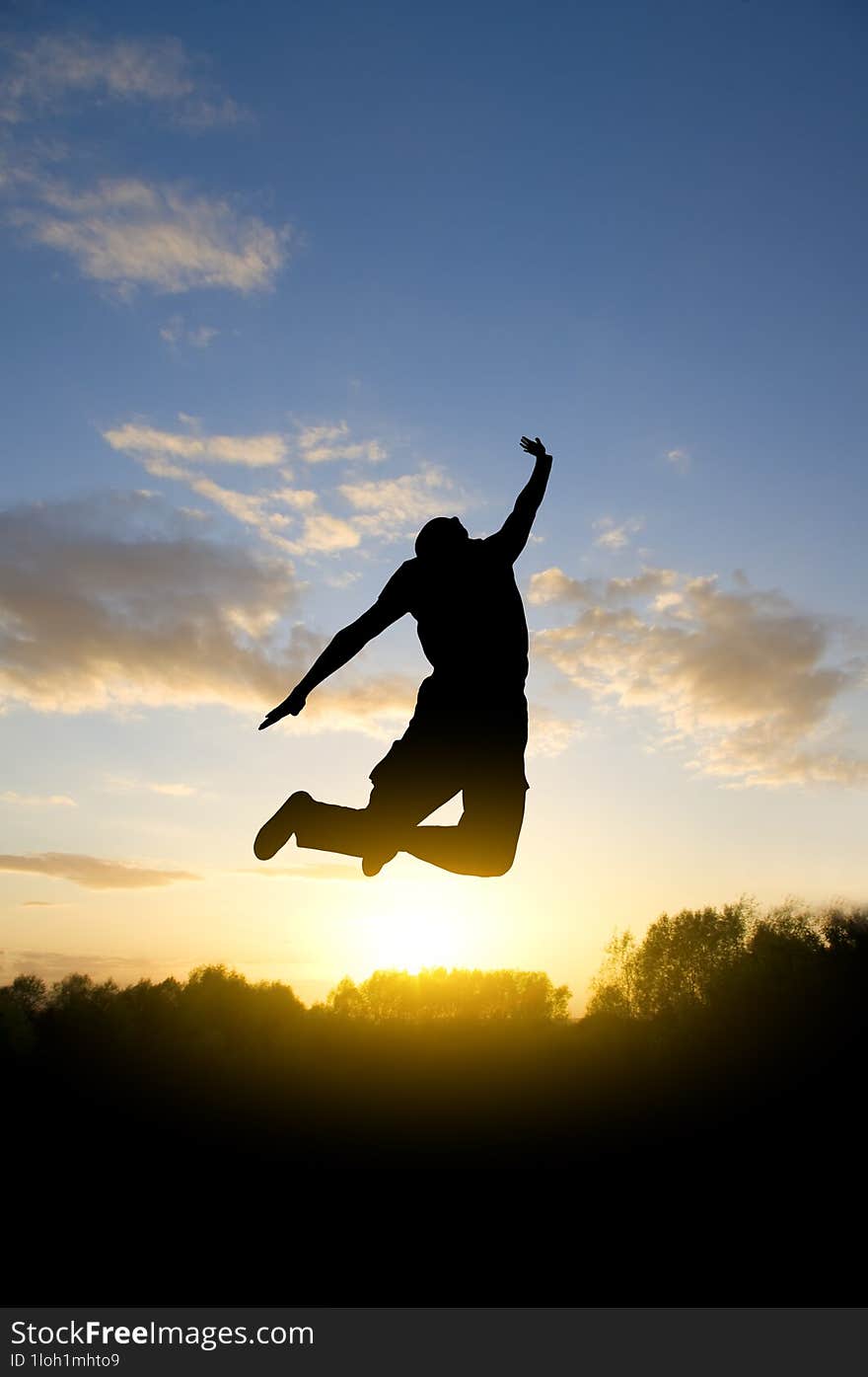 happy young man jumping  against evening sky background