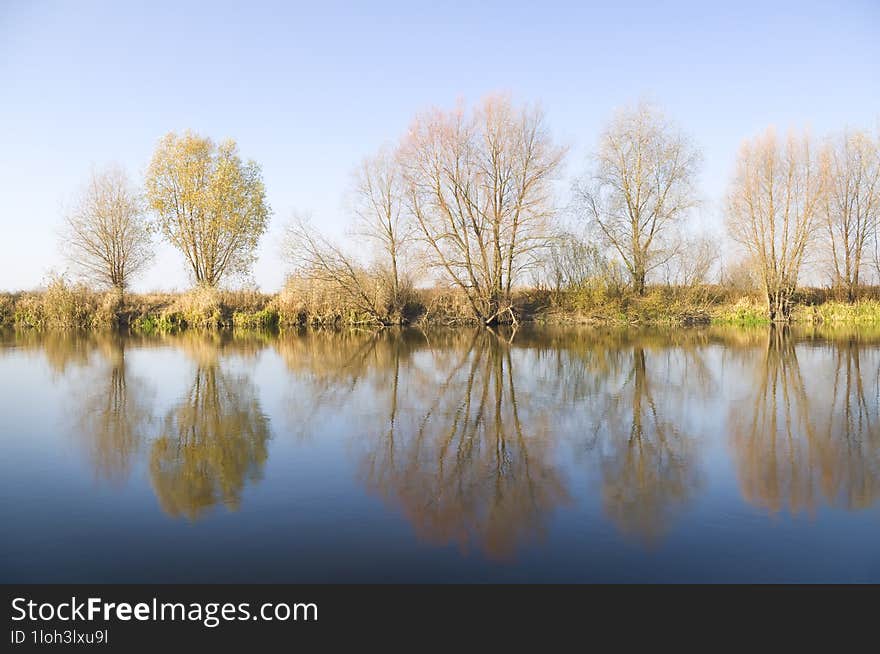 Coast of the autumn river reflected in its waters