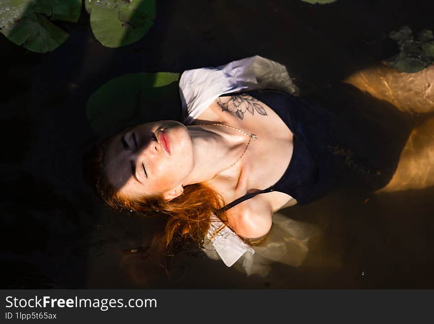 Red Hair Woman Swimming In Summer Lake With Lily