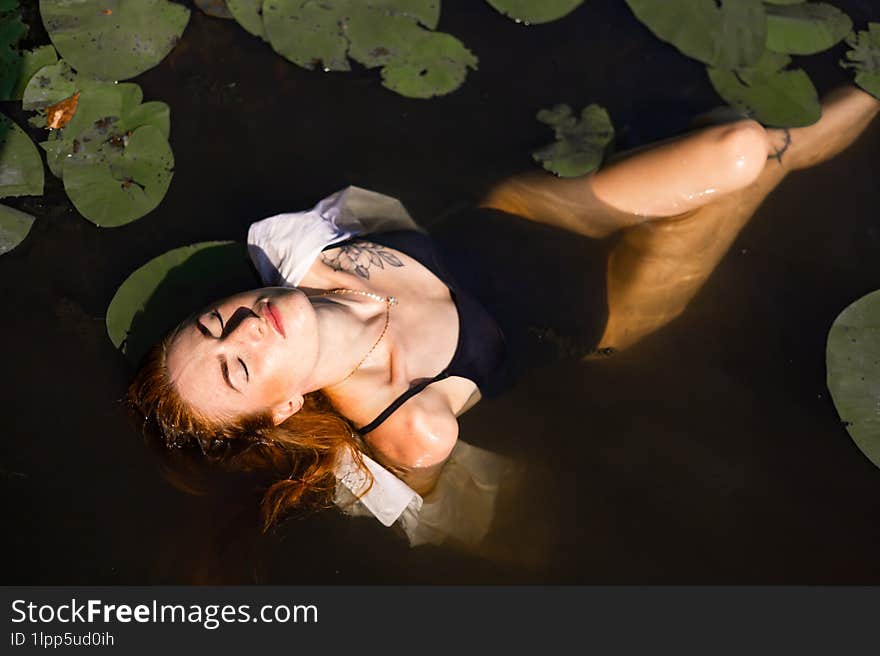 Red Hair Woman Swimming In Summer Lake With Lily