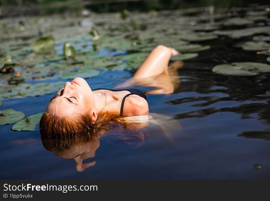 Red Hair Woman Swimming In Summer Lake With Lily