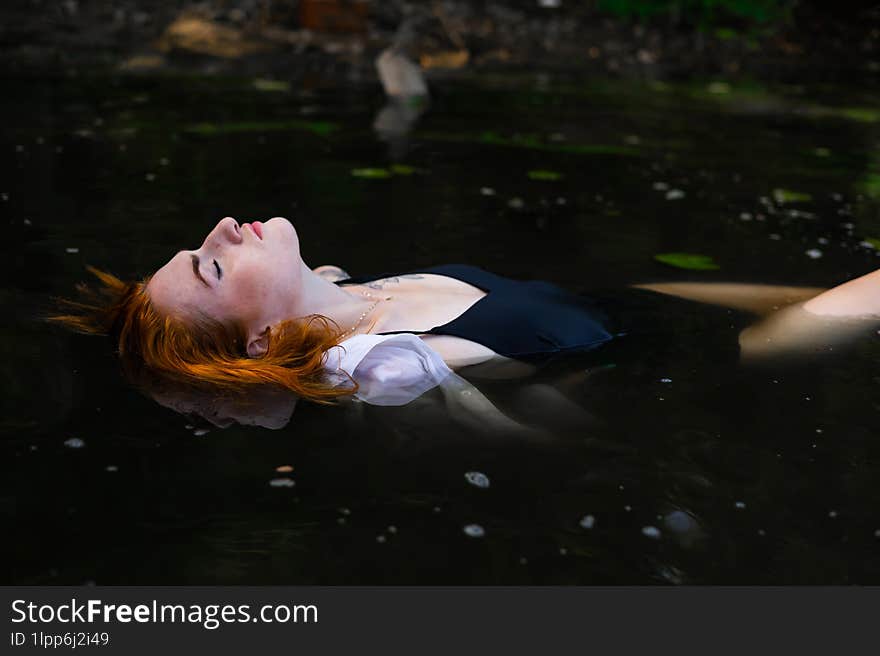 Red Hair Woman Swimming In Summer Lake With Lily