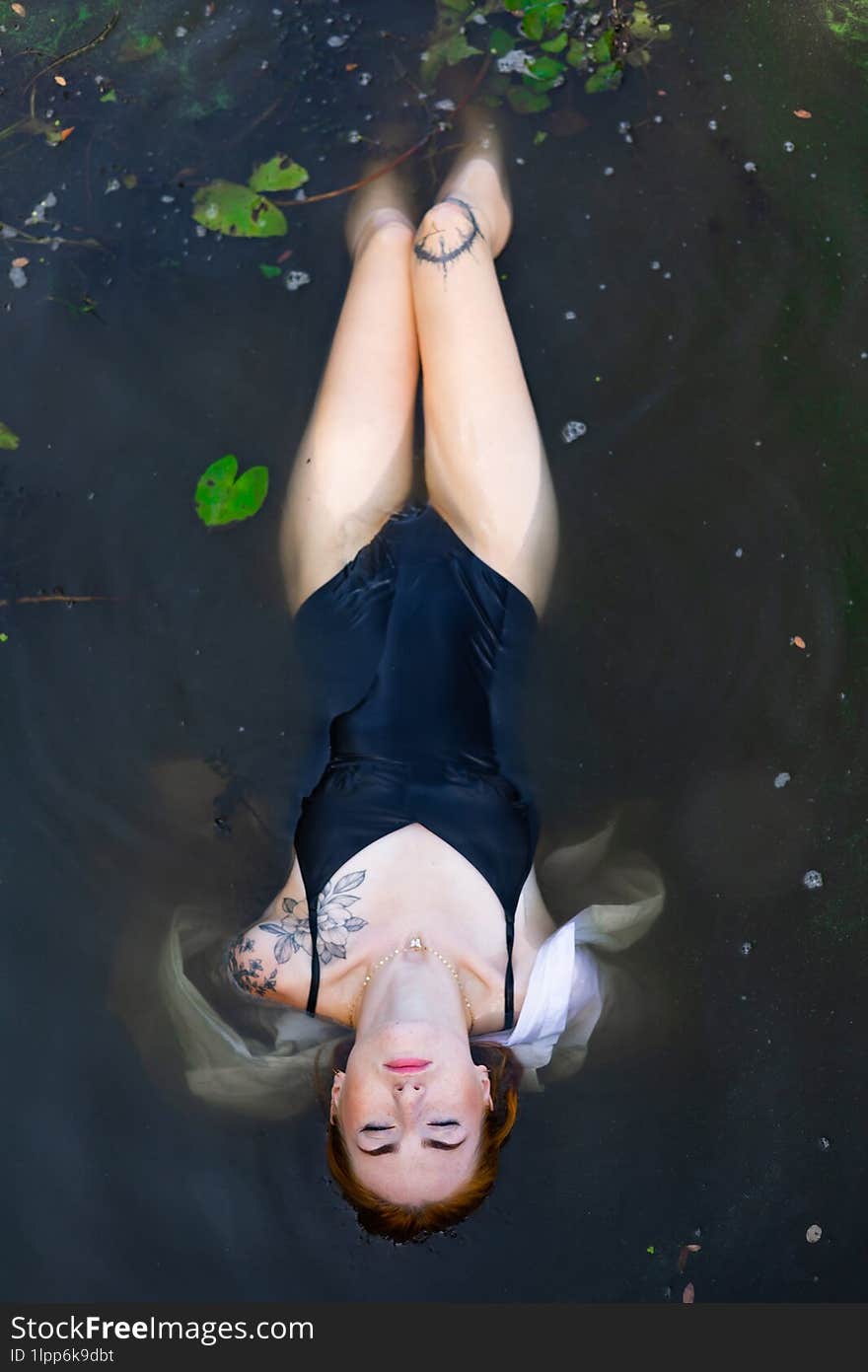 Red hair woman swimming in summer lake with lily