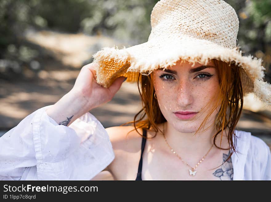 Red hair woman in swimsuit and summer hat near river.