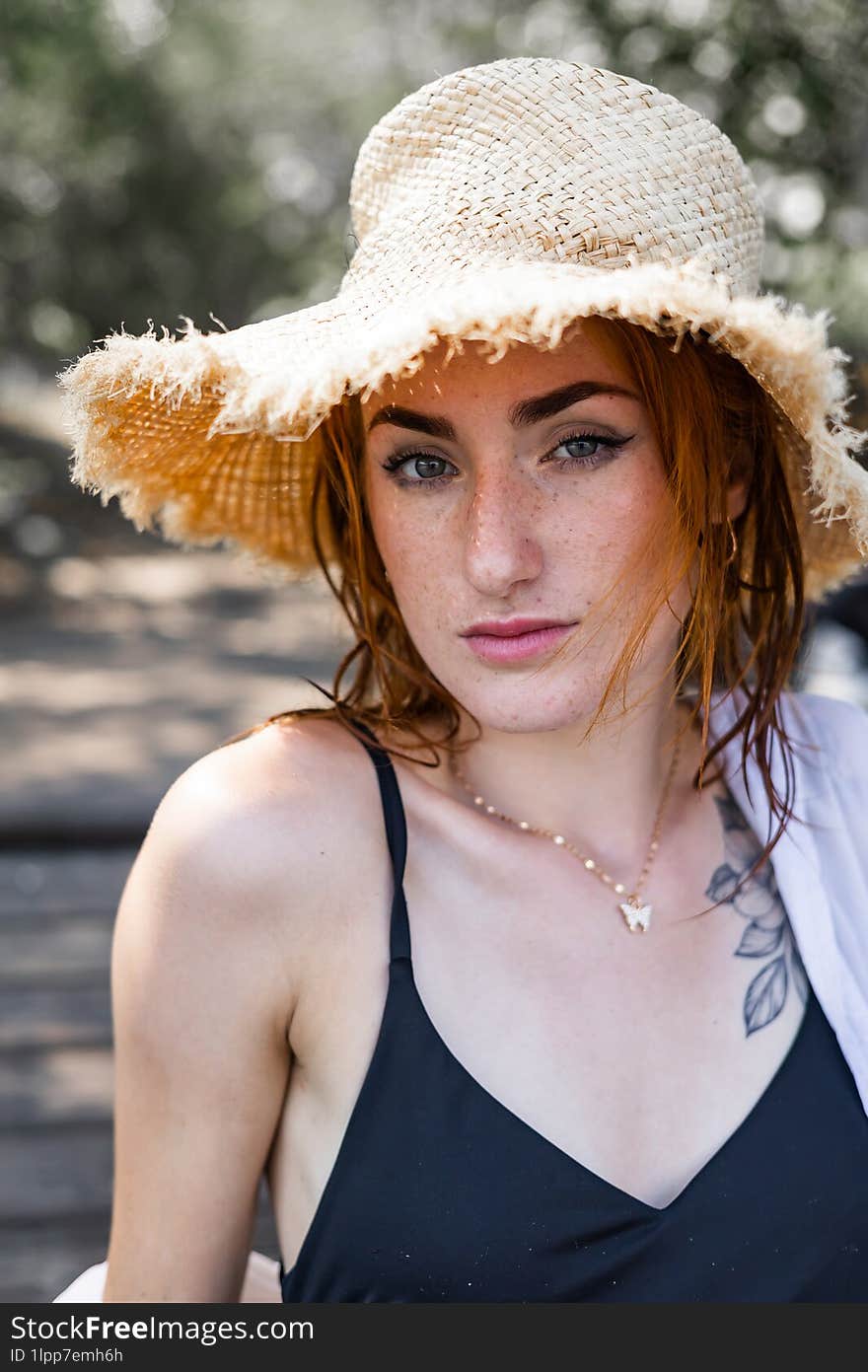 Red hair woman in swimsuit and summer hat near river.