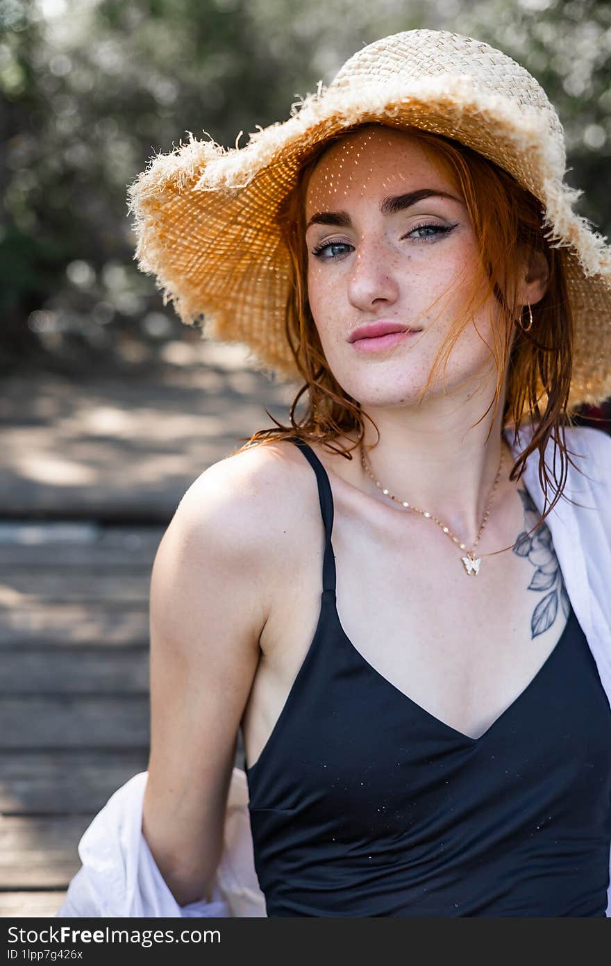 red hair woman in summer hat and swim suit outdoor near river.