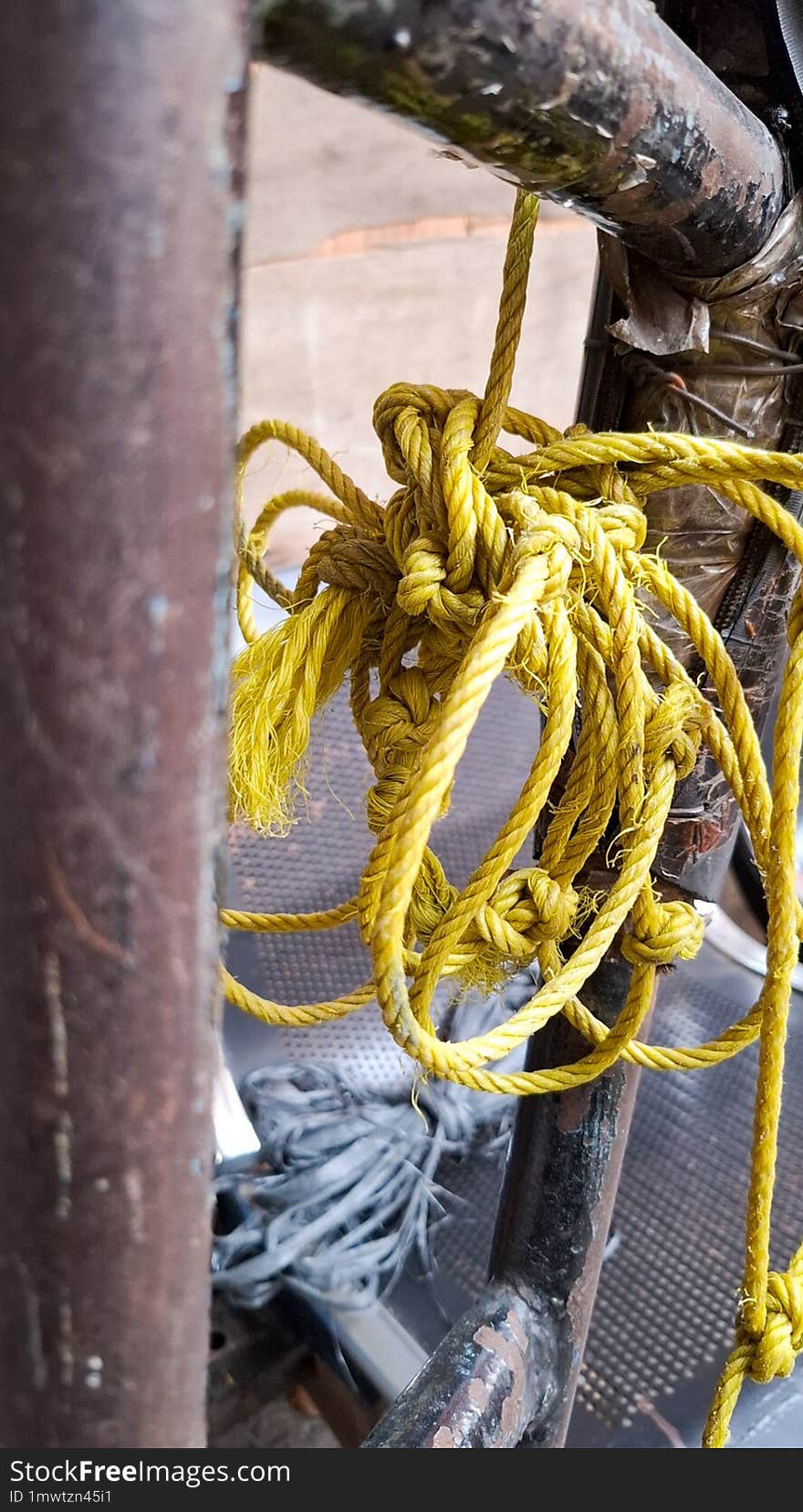 Close-up of an old yellow rope with a messy knot.