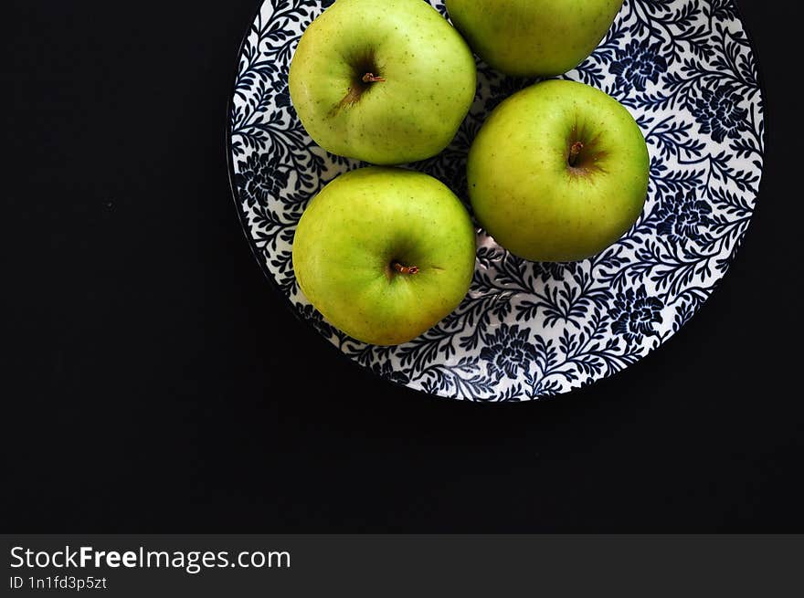 plate with green apples on a black background