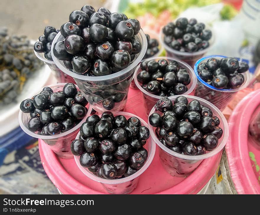 Fresh Java Plums are sold in small cups on the roadside