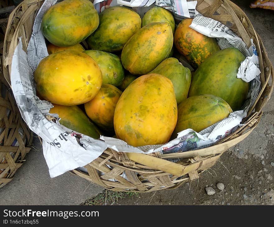 Fresh papayas are sold in rattan basket on the side of road