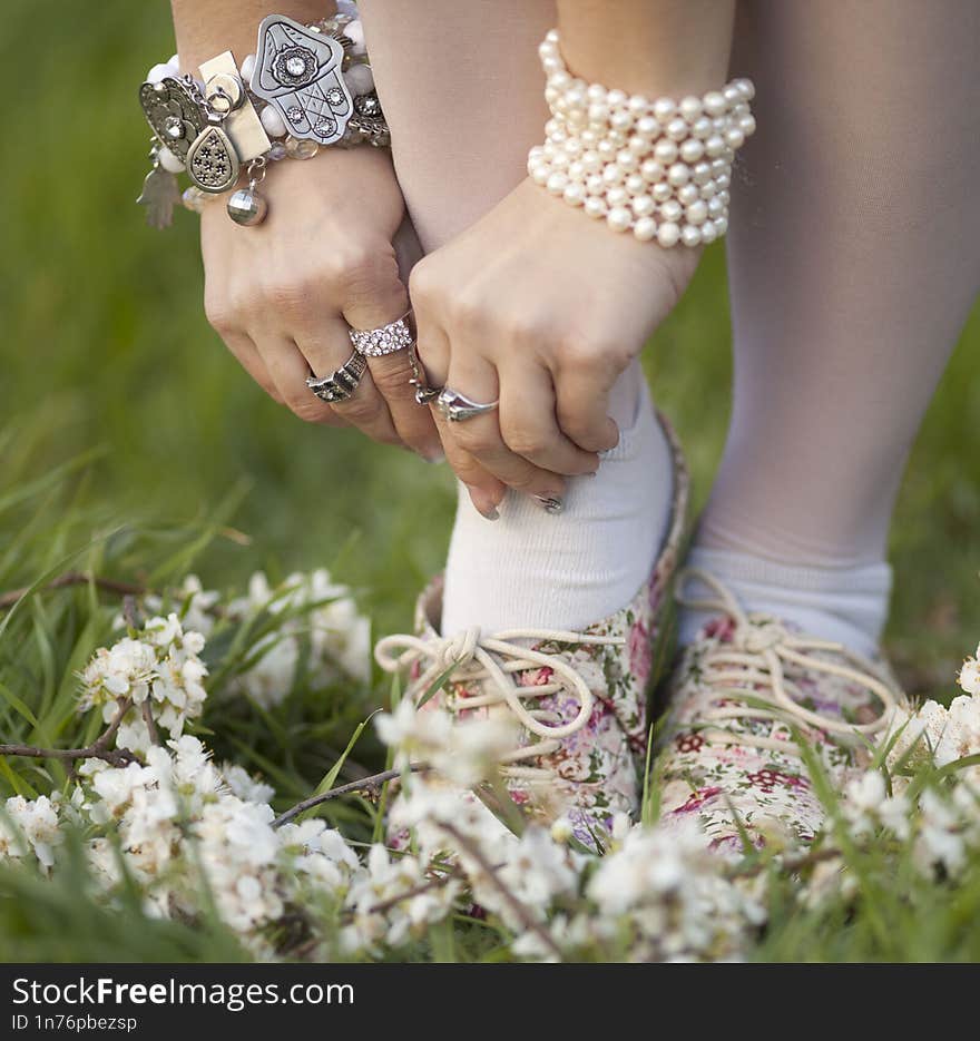 Feet of female relaxing at public park with pink flowers fall on green grass, nearly the end of winter and starting to summer time