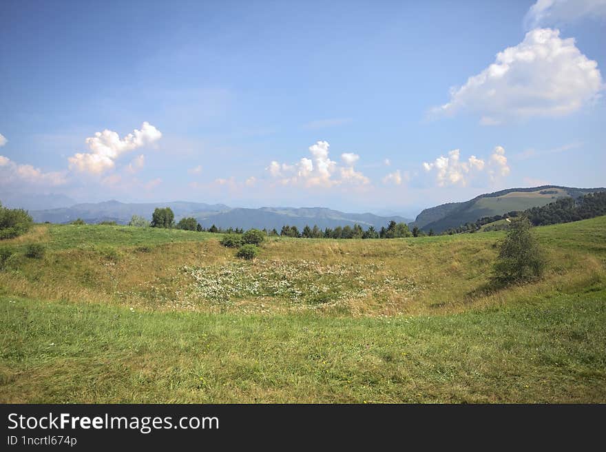 Field on a mountain slope with ridges on the horizon on a sunny day