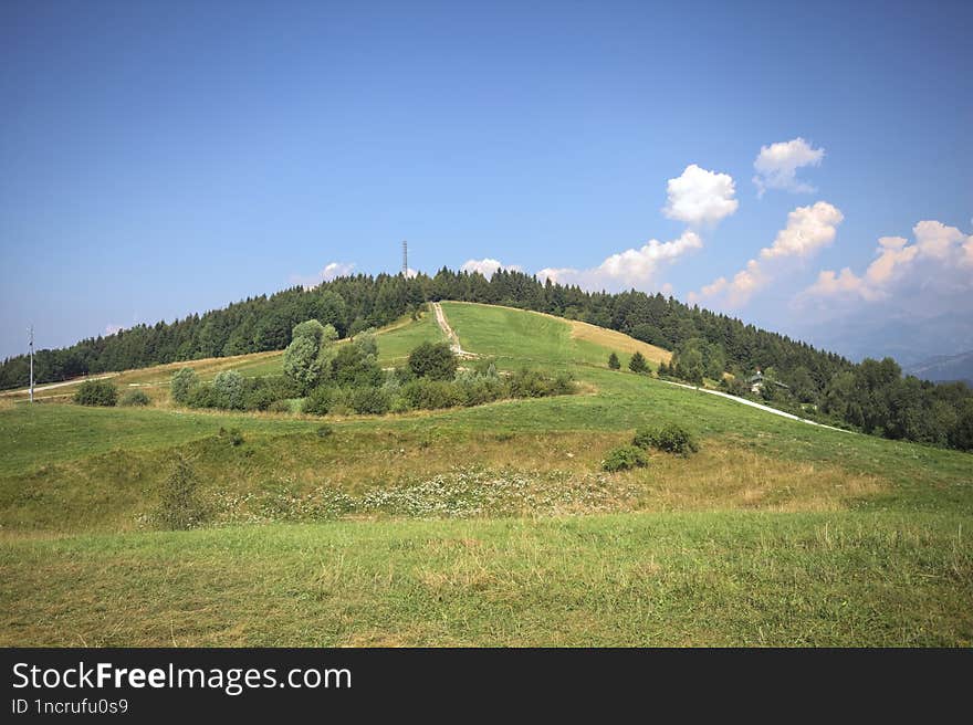 Small plateau on a mountain peak with groves and antennae on the peaks in the distance. Small plateau on a mountain peak with groves and antennae on the peaks in the distance