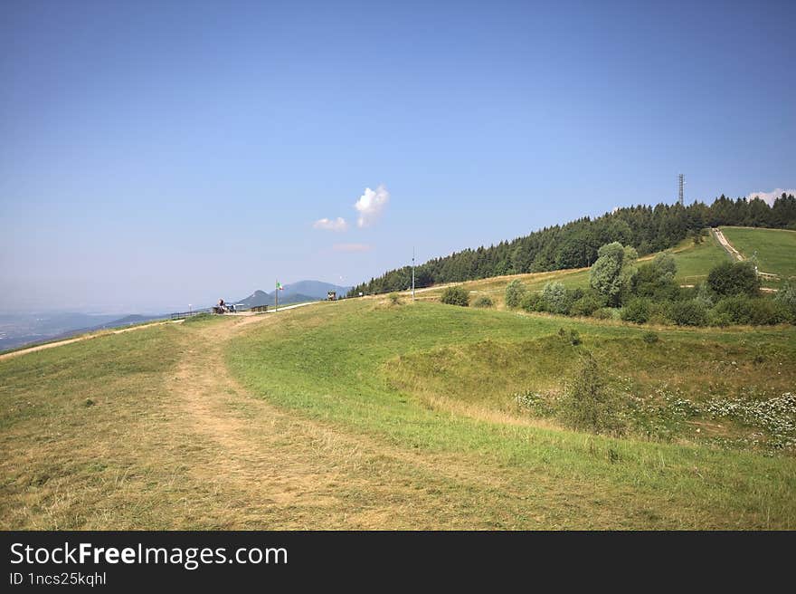 Small plateau on a mountain peak with groves and antennae on the peaks in the distance. Small plateau on a mountain peak with groves and antennae on the peaks in the distance