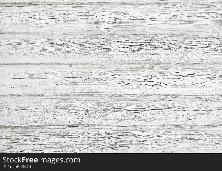 The grunge vintage texture of a wooden fence covered with peeling white paint, a versatile light background