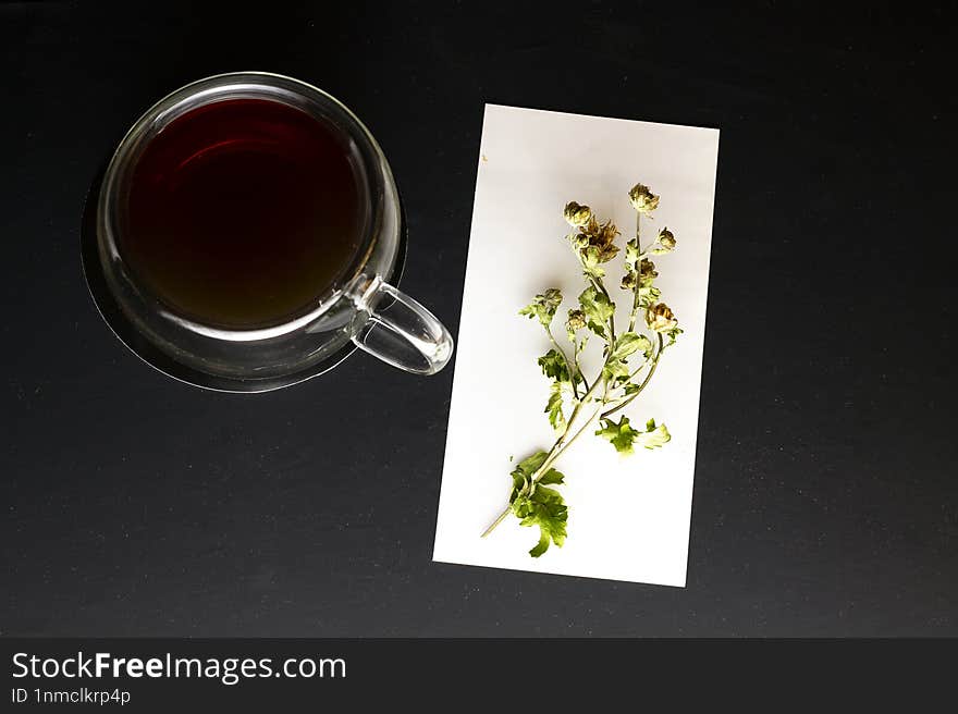 Top View Of Black Mug With Tea On Black Background With Dried Flower Near Mug