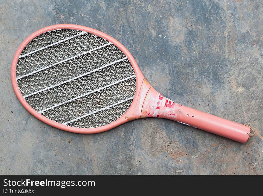 Broken Mosquito Racket On Gray Abstract Textured Cement Background.