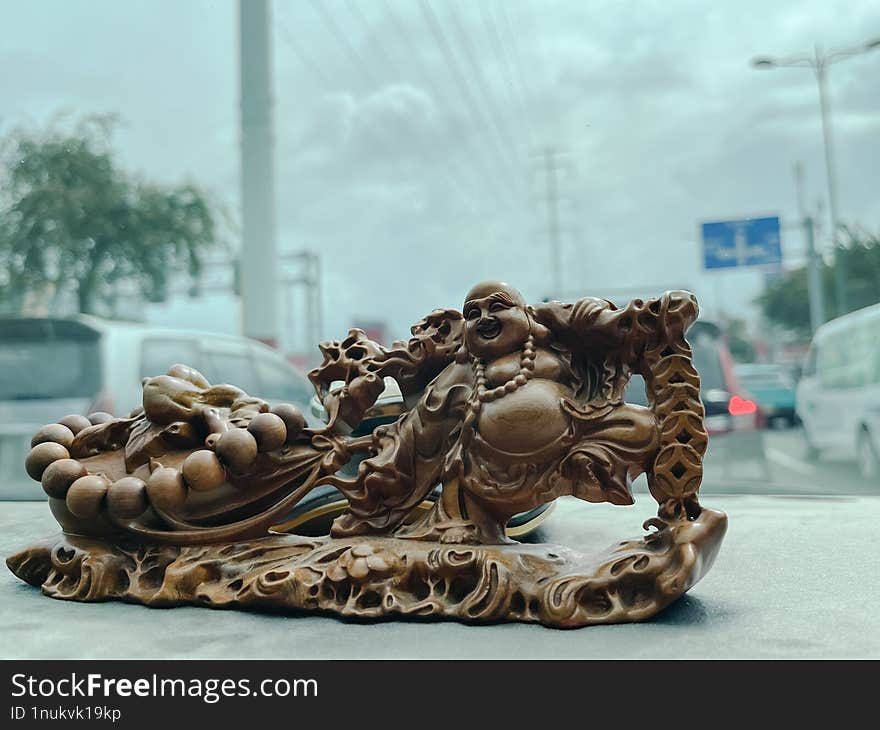 A wooden carving of a laughing Buddha, also known as Hotei or Budai