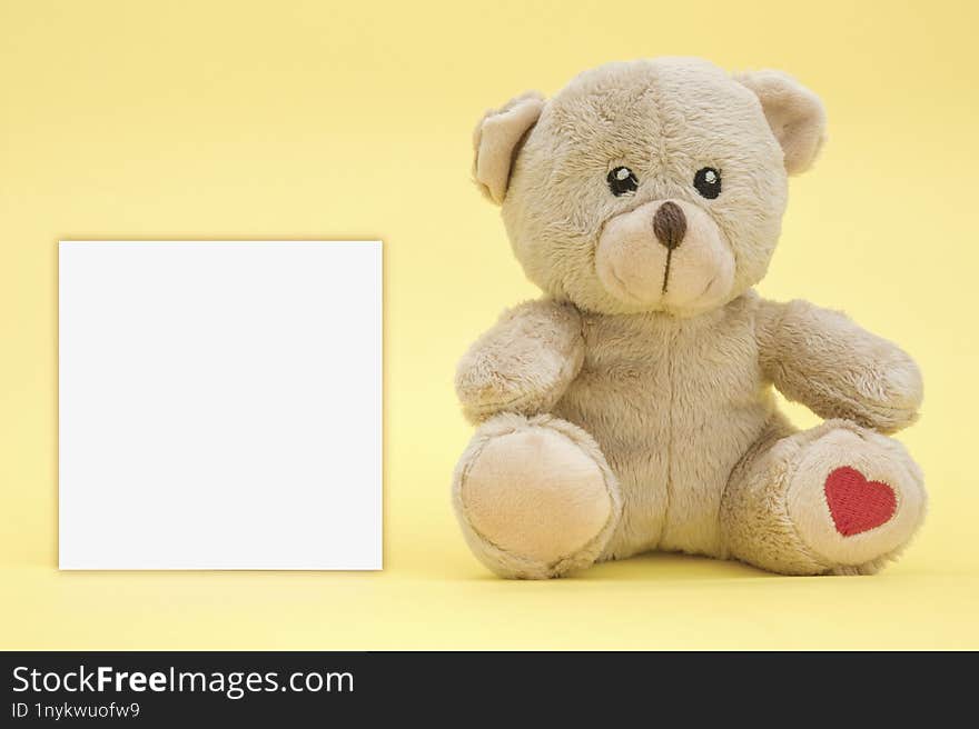 baby toy teddy bear and one blank card for text on a yellow background