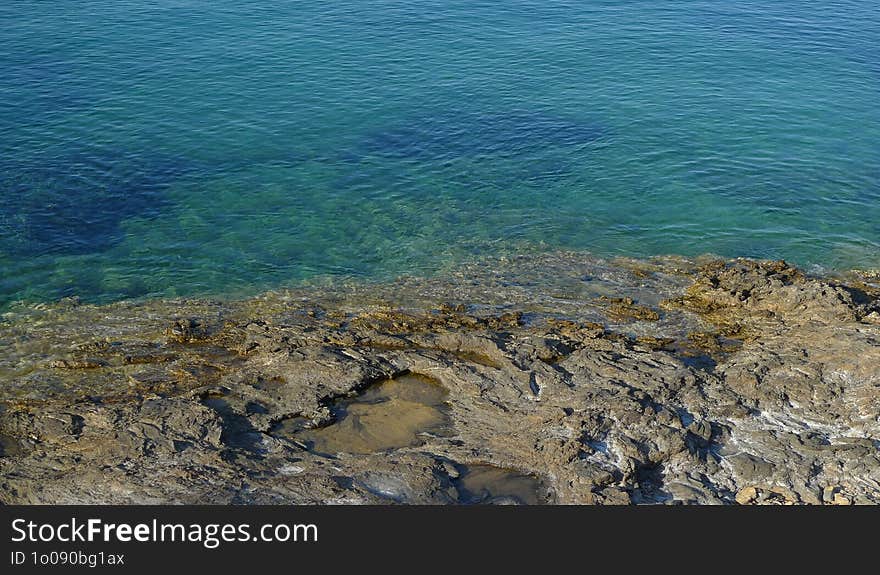 A rocky Mediterranean beach with clear, blue water in a greek island