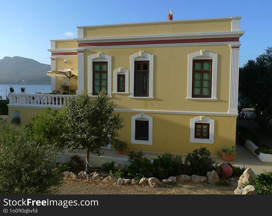 A yellow, traditional-style house located in a coastal area of Leros, a Greek island