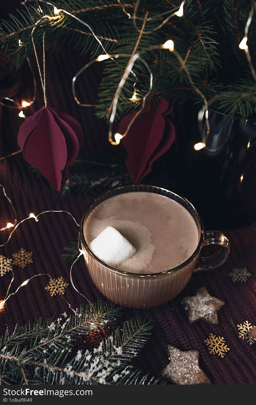 Cozy Christmas still life with hot chocolate, fir branches, Christmas cookies and lights.