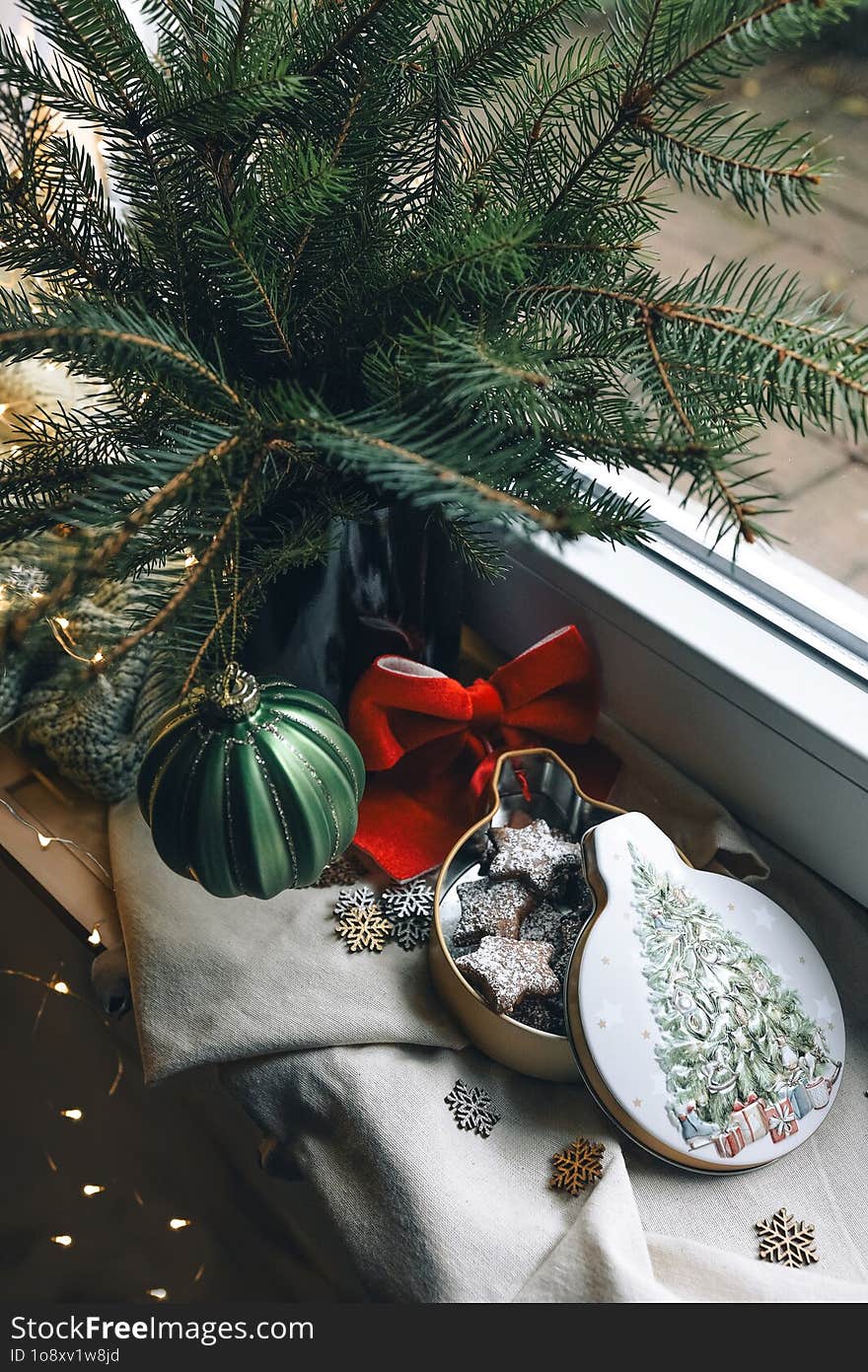 Cozy Christmas Still Life On The Window With Fir Branches, Christmas Cookies And Lights. A Vase With Fir Branches Stands On The Wi