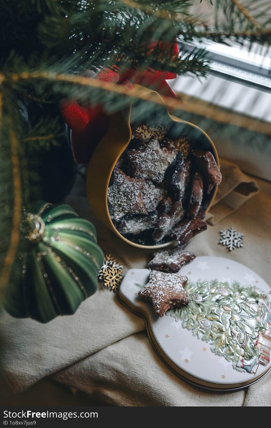 Cozy Christmas still life on the window with fir branches, Christmas cookies and lights. A vase with fir branches stands on the wi