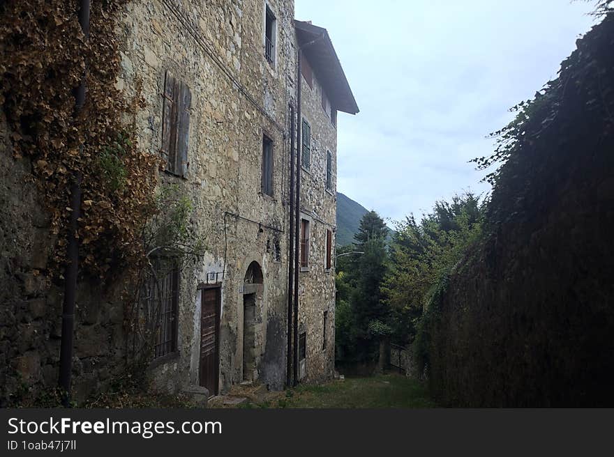 Sloppy cobbled path between a stone wall and a stone building in the mountains. Sloppy cobbled path between a stone wall and a stone building in the mountains