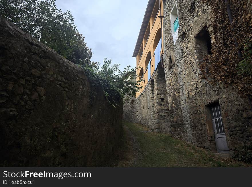 Sloppy cobbled path between a stone wall and a stone building in the mountains. Sloppy cobbled path between a stone wall and a stone building in the mountains