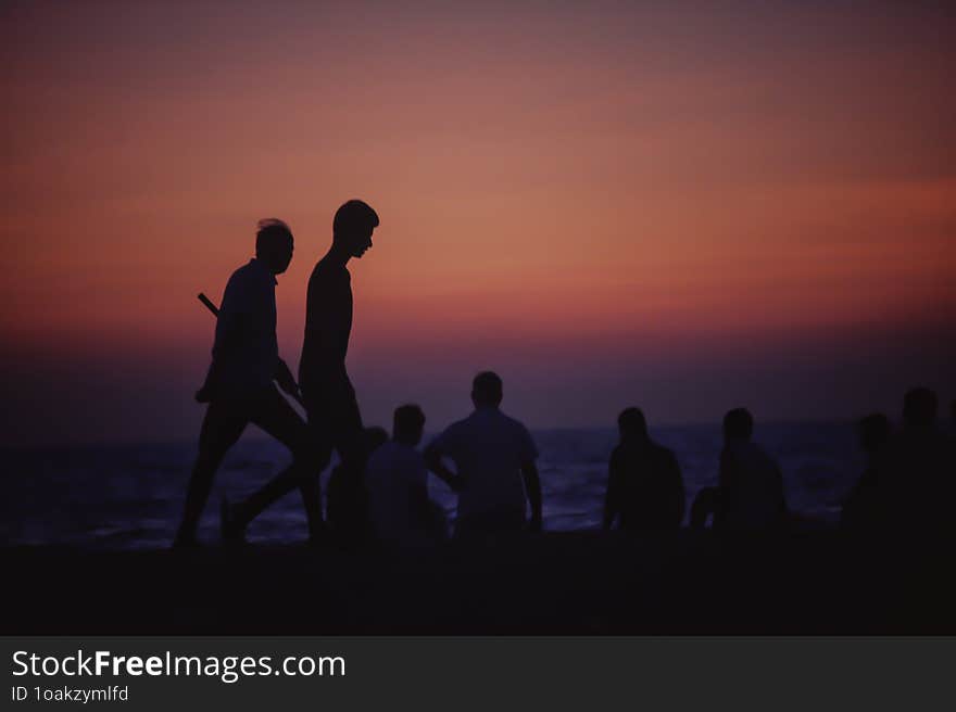 Silhouette Of People Walking In The Sunset On A Beach