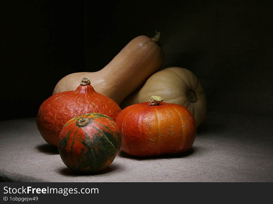 Still Life With Five Red And White Pumpkins Arranged On A Linen Drapery Surface